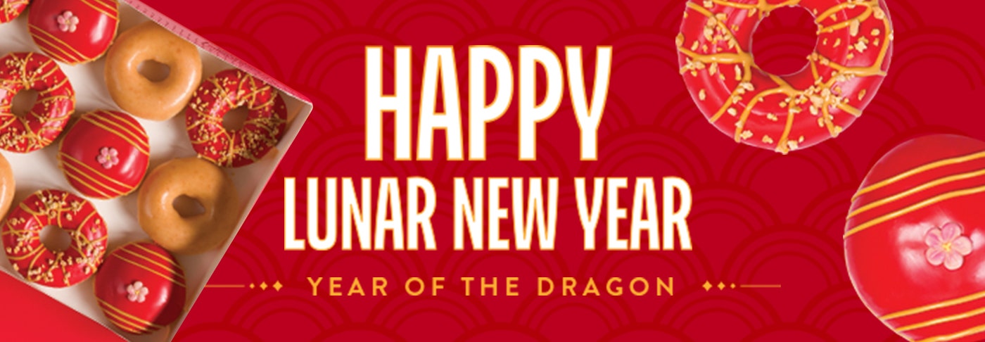 Banner featuring the words Happy Lunar New Year in white and gold text on a red background. A red iced ring doughnut with gold decoration and a red iced filled doughnut with a sugar flower in the middle, as well as a dozen box image - all top down.