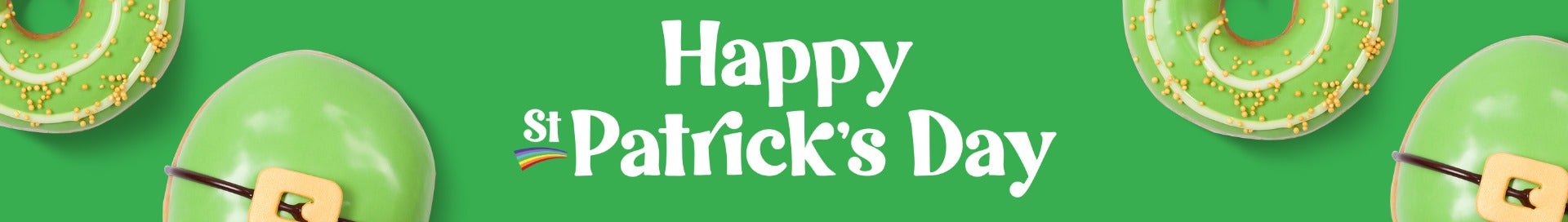 Krispy Kreme Limited Time Offer St Patrick's Day Doughuts Banner featuring the words Happy St Patrick's Dayu in white text on a green background. Surrounded by green iced doughnuts, one with a belt buckle decoration, the other with a white spiral and gold sprinkles